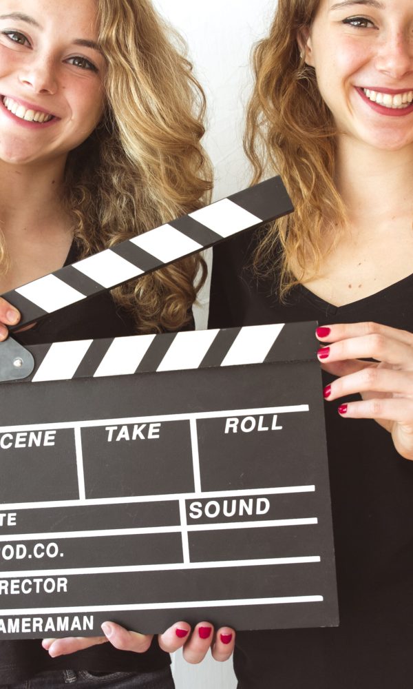close-up-smiling-wins-sister-holding-clapperboard-hands